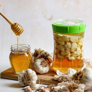 tarro con de cristal con tapa verde conteniendo ajos fermentados