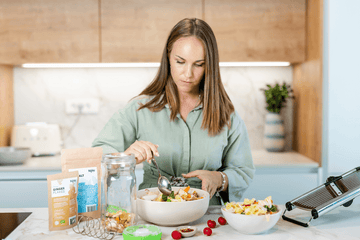 Mujer en una cocina moderna removiendo verduras en un bol para una receta de fermentación.