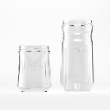 Dos tarros de vidrio Kefirko de diferente tamaño para fermentación casera, vacíos y sobre fondo blanco.