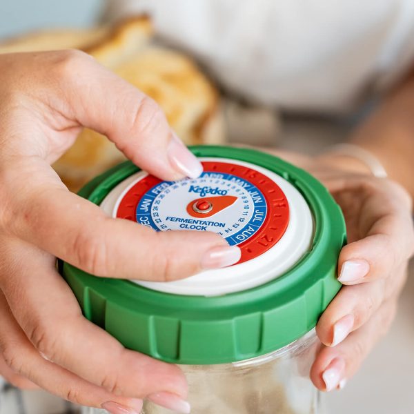 Manos ajustando el reloj en la tapa de un tarro para controlar el tiempo de fermentación de la masa madre.