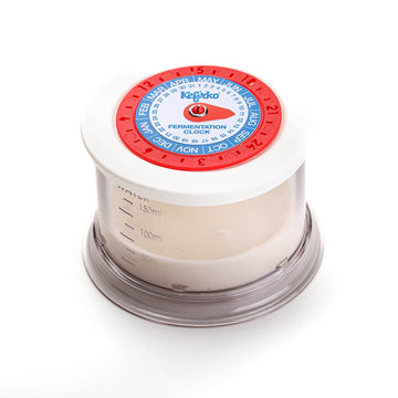 Primer plano del reloj de fermentación del kit Kefirko sobre el vaso medidor con masa madre.