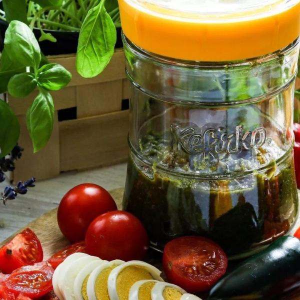 tarro de cristal con pesto fermentado junto a tomate y huevo en rodajas