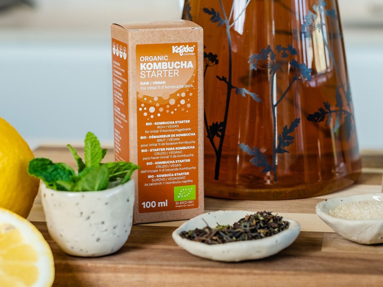 Ingredientes para la receta kombucha: starter, té, azúcar, limón y menta junto a un tarro.