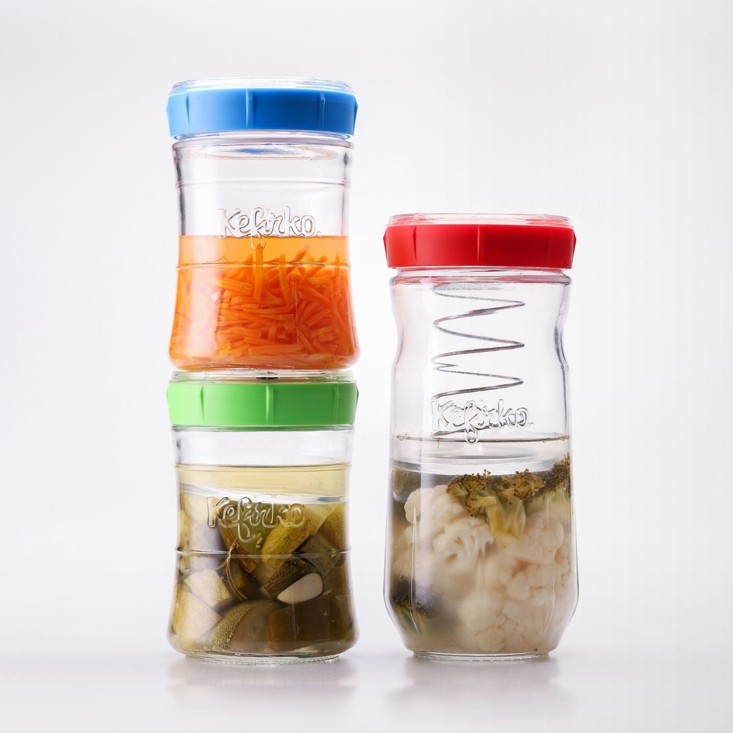 tres tarros de cristal con tapas de colores fermentando verduras